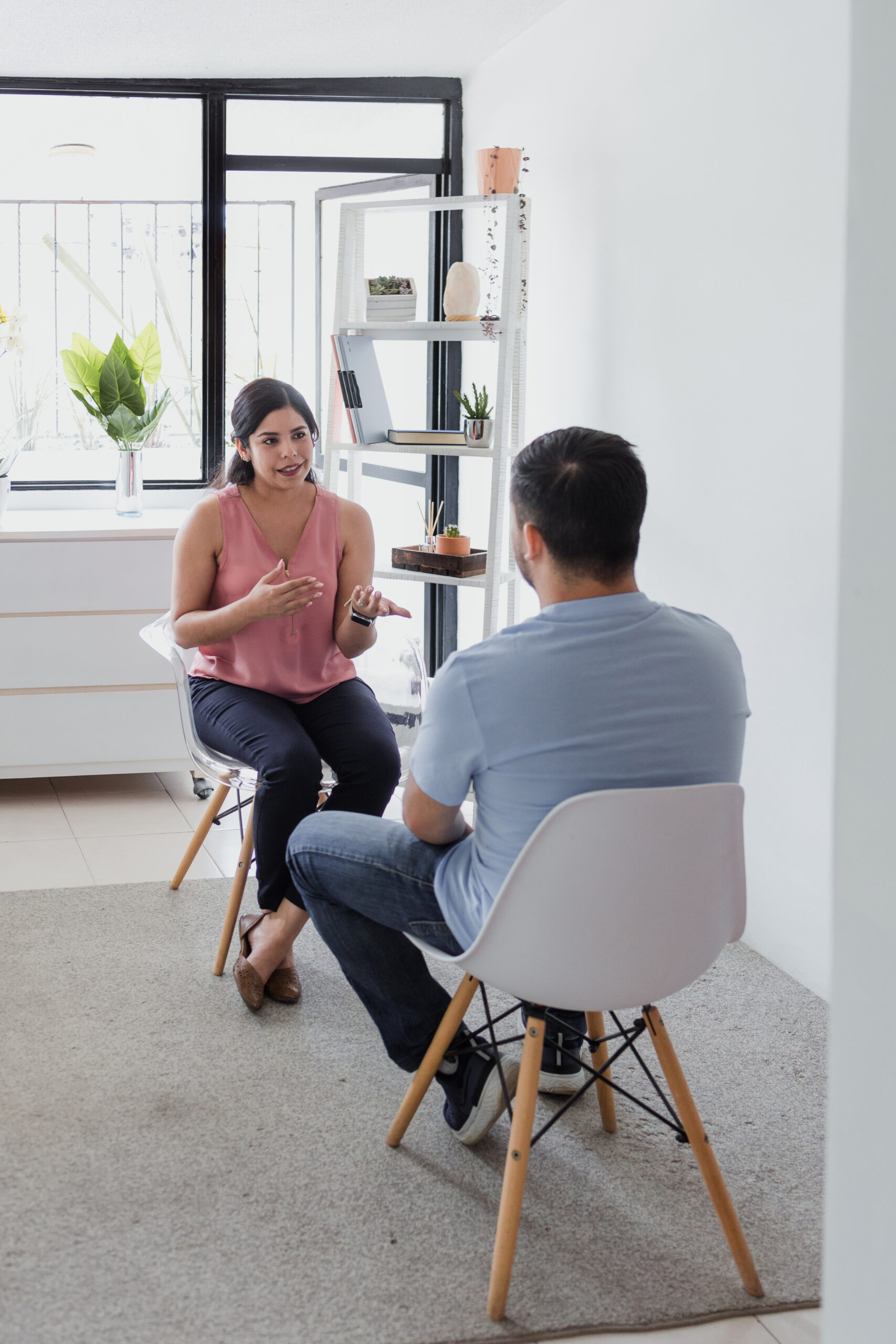 Hispanic young woman psychologist with male patient telling about mental problems while doctor is listening and making notes. Psychotherapy concept in Mexico Latin America